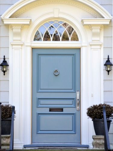 a blue front door with two planters on either side