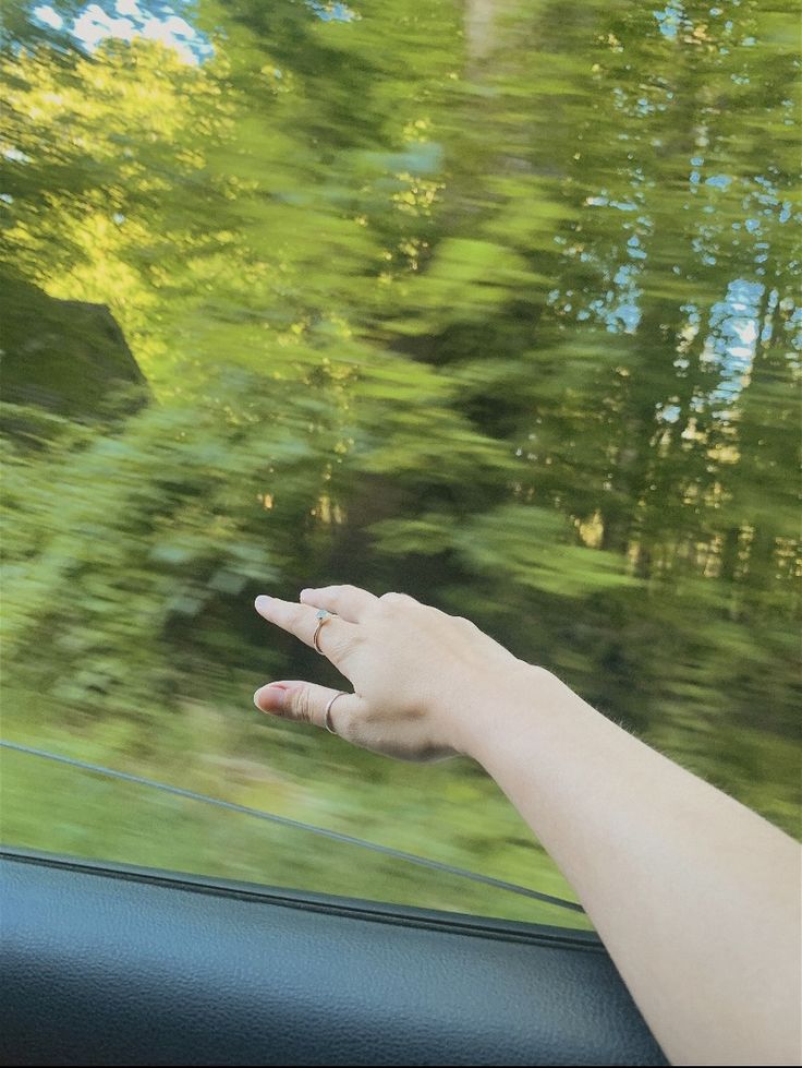 a person's hand on the dashboard of a car with trees in the background