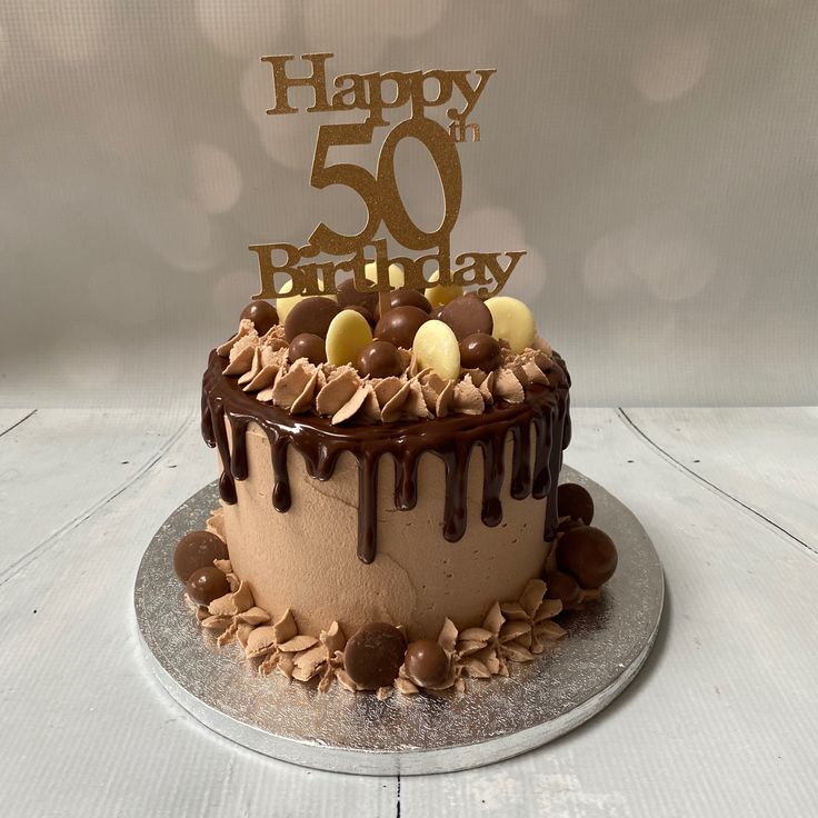 a birthday cake with chocolate frosting and nuts on top that says happy 50 th birthday