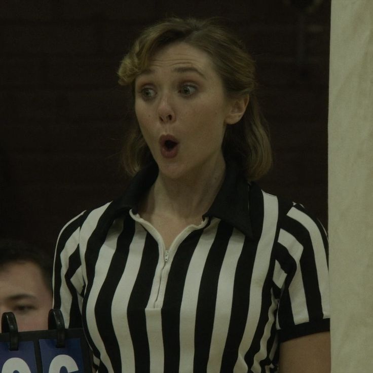 a woman in a referee's uniform making a surprised face