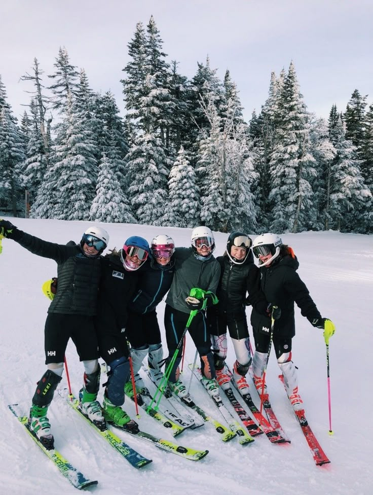 a group of people on skis posing for a photo in front of some trees