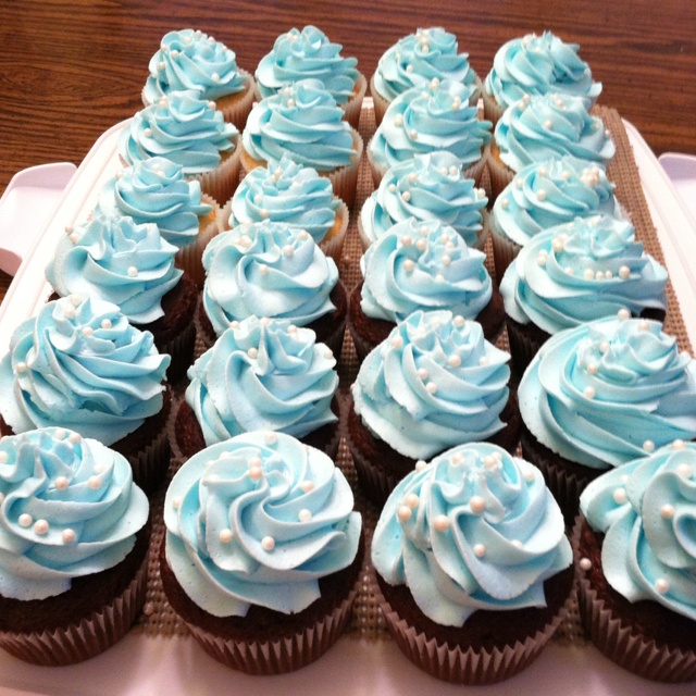 cupcakes with blue frosting are arranged on a tray