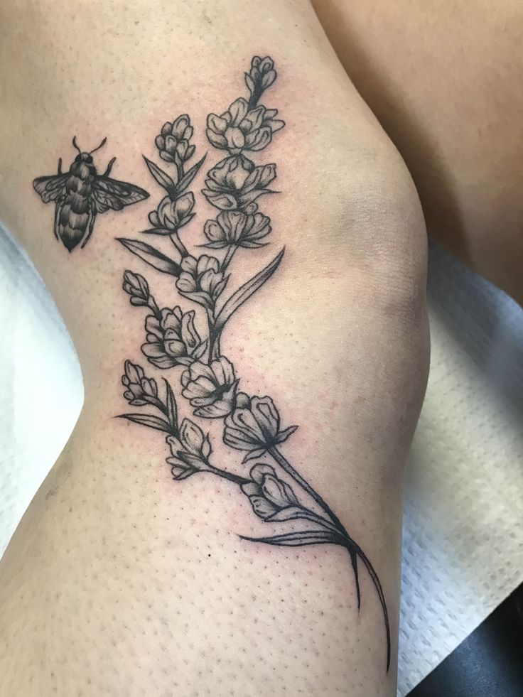 a black and white photo of a flower on the thigh with a butterfly sitting on it