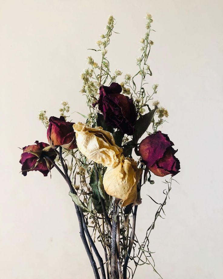 a vase filled with flowers on top of a wooden table next to a white wall