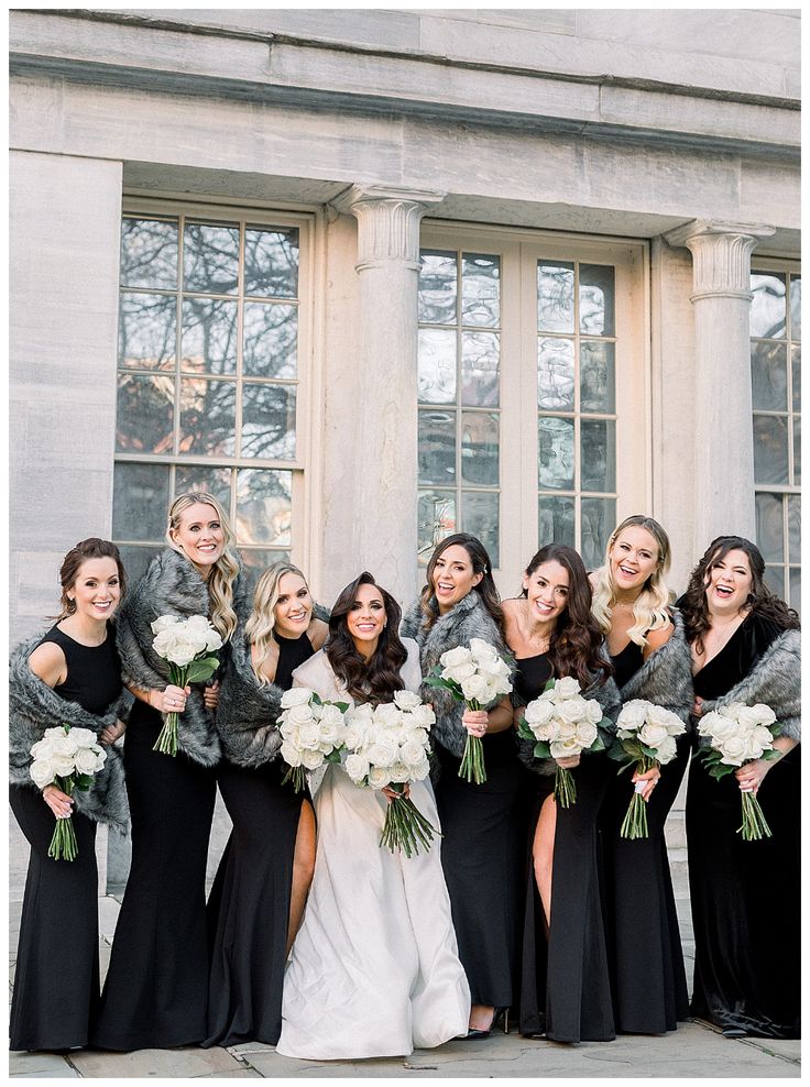 a group of women standing next to each other in front of a building holding bouquets