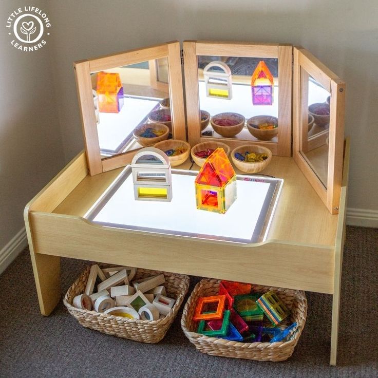 a child's play table with toys in baskets on the bottom and an open window