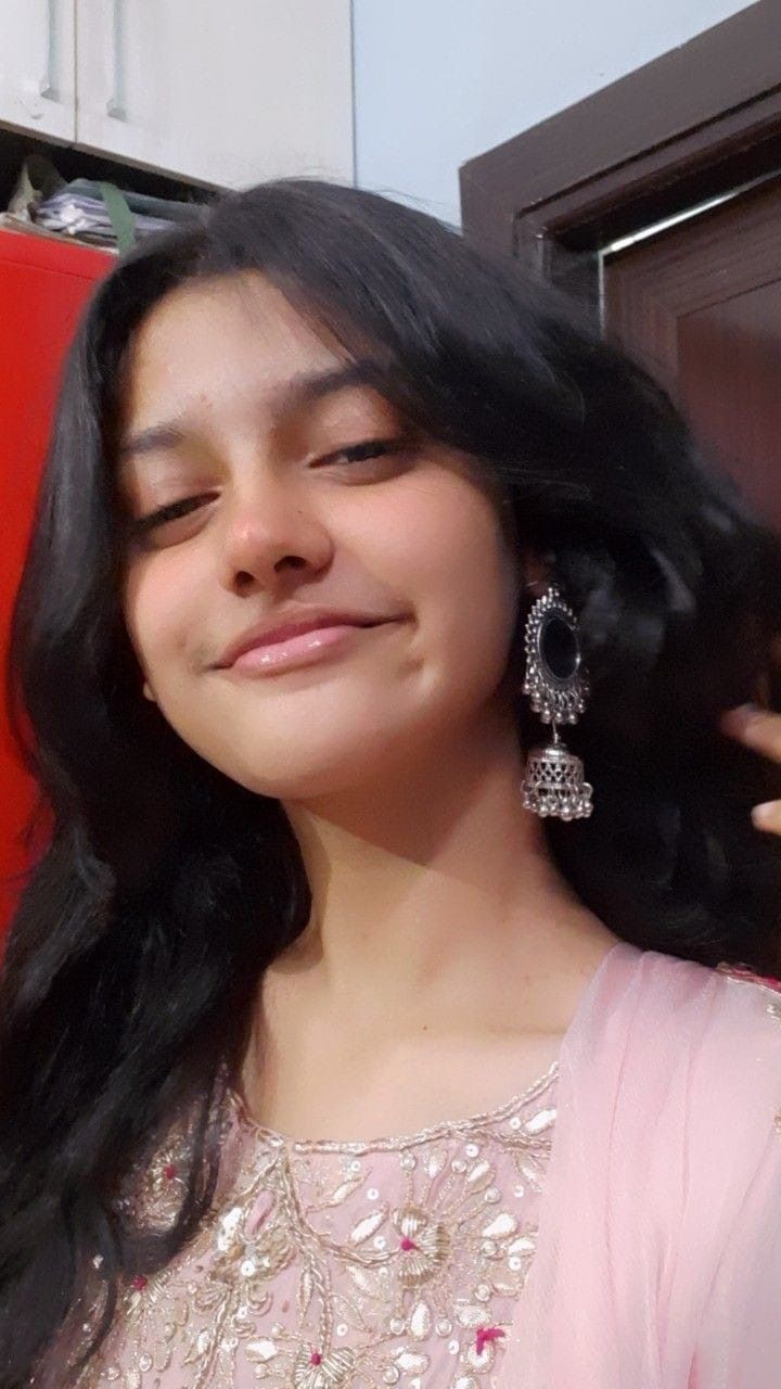 a woman with long black hair is smiling at the camera and wearing earrings on her head