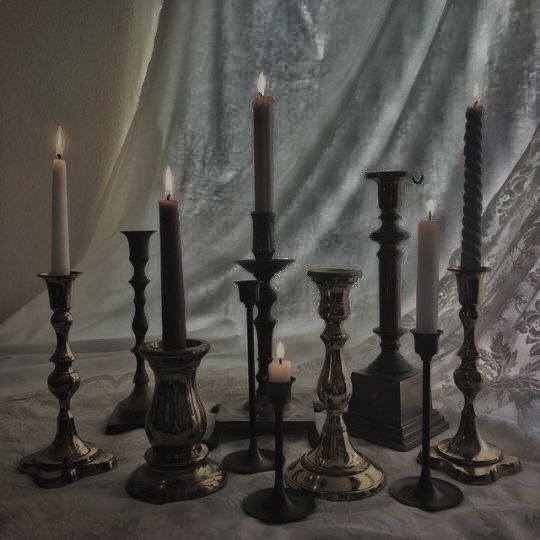 a group of candles sitting next to each other on top of a white table cloth