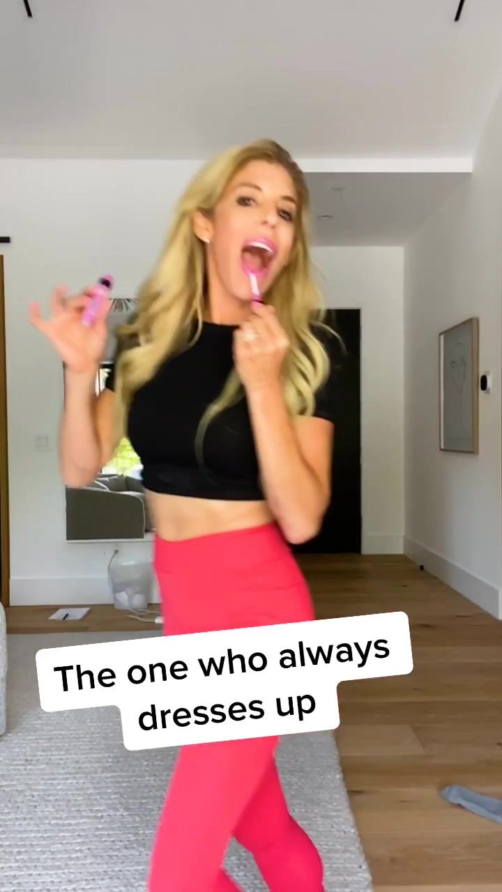 a woman in pink skirt and black top holding up a toothbrush with the caption'the one who always dresses up '