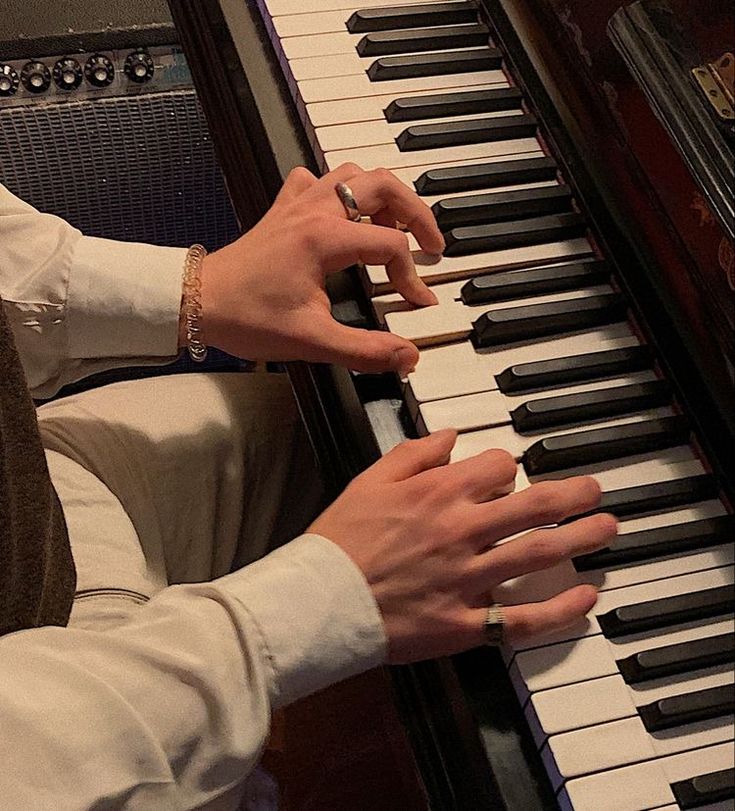 two hands are playing the piano while another person is wearing a watch on their wrist