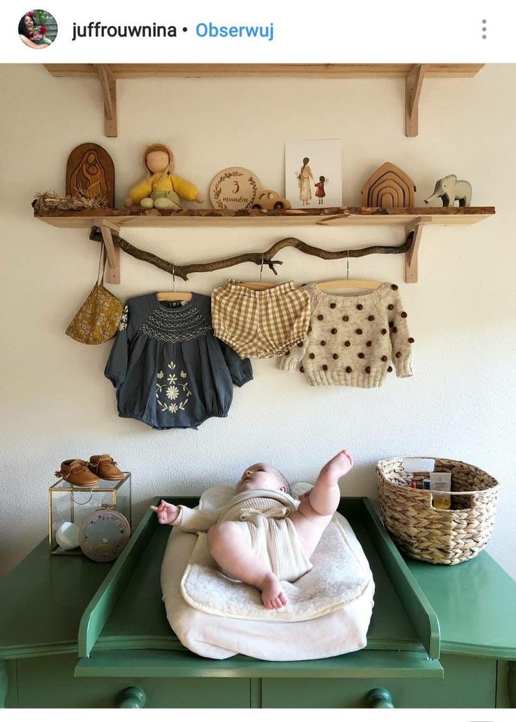 a baby laying on top of a green table in front of a wall mounted shelf