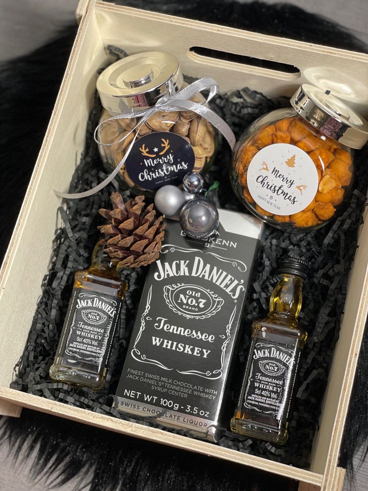 an open gift box containing jack daniels whiskey, pine cones and other condiments