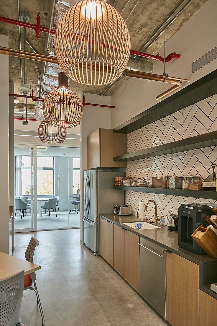 an open kitchen and dining area with wooden cabinets, counter tops, and hanging lights