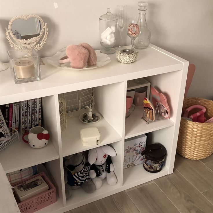 a white shelf filled with lots of toys and other items next to a wall mounted mirror