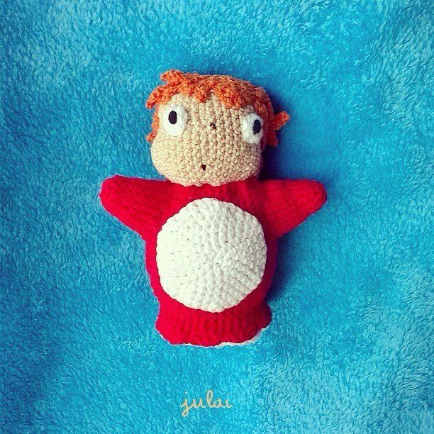 a crocheted doll laying on top of a blue blanket