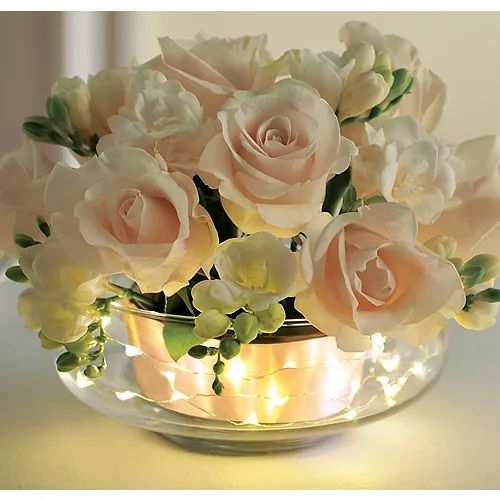 a vase filled with lots of white flowers on top of a table next to a mirror