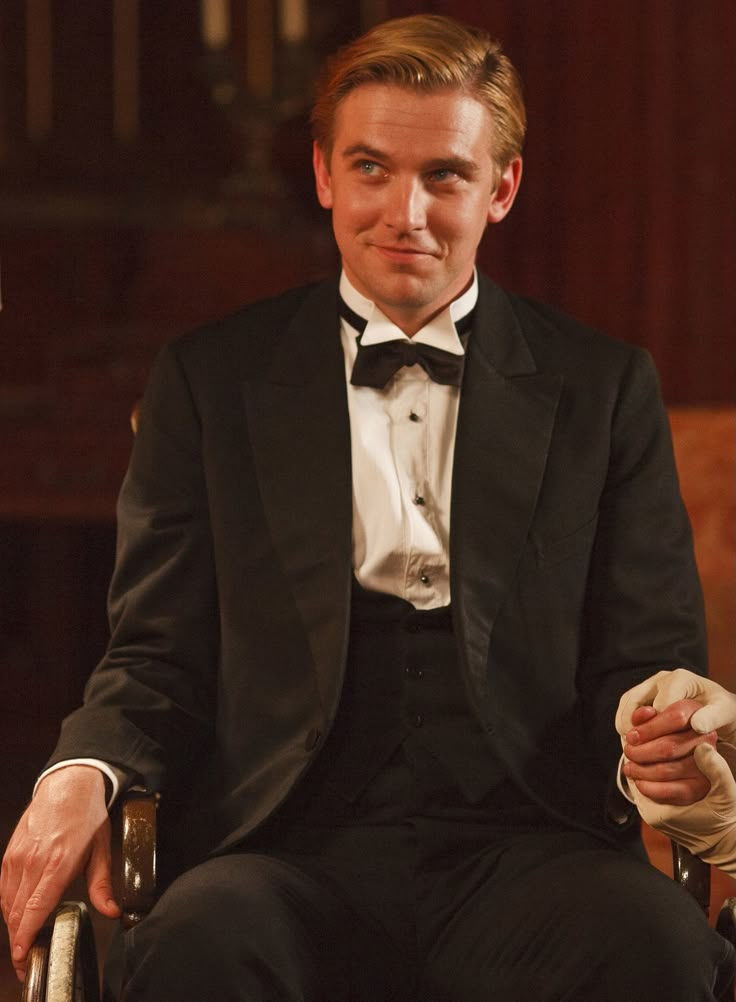 a man in a tuxedo sitting on a chair