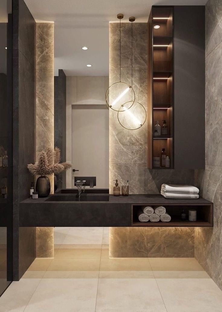 a bathroom with marble walls and flooring, lights on the wall above the sink