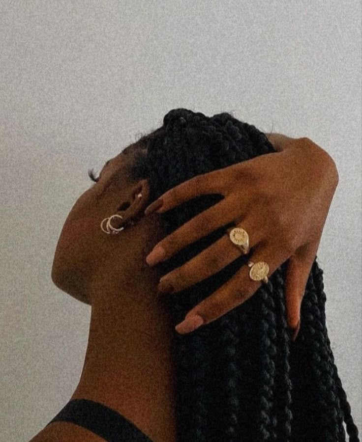 a woman with braids and rings on her head holding her hand up to her ear