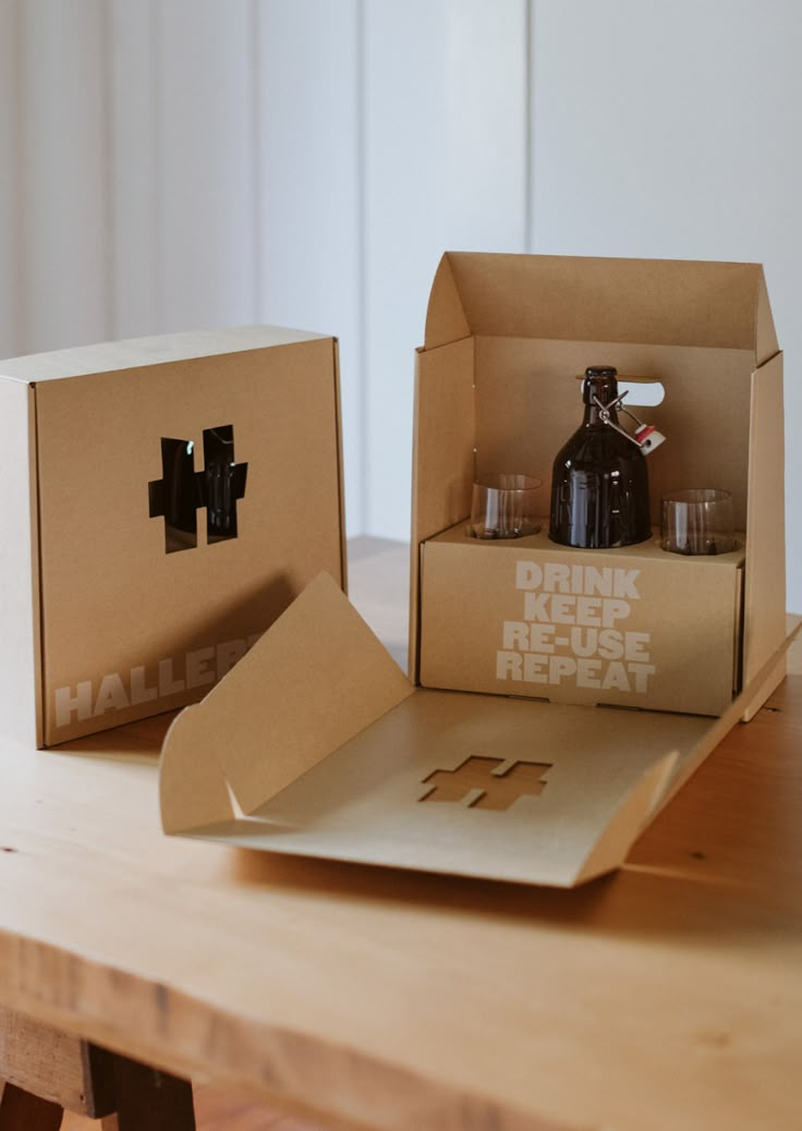 two cardboard boxes with drinks inside sitting on a table next to each other, one opened and the other closed