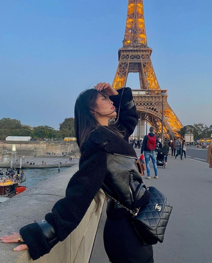 a woman leaning on a wall in front of the eiffel tower