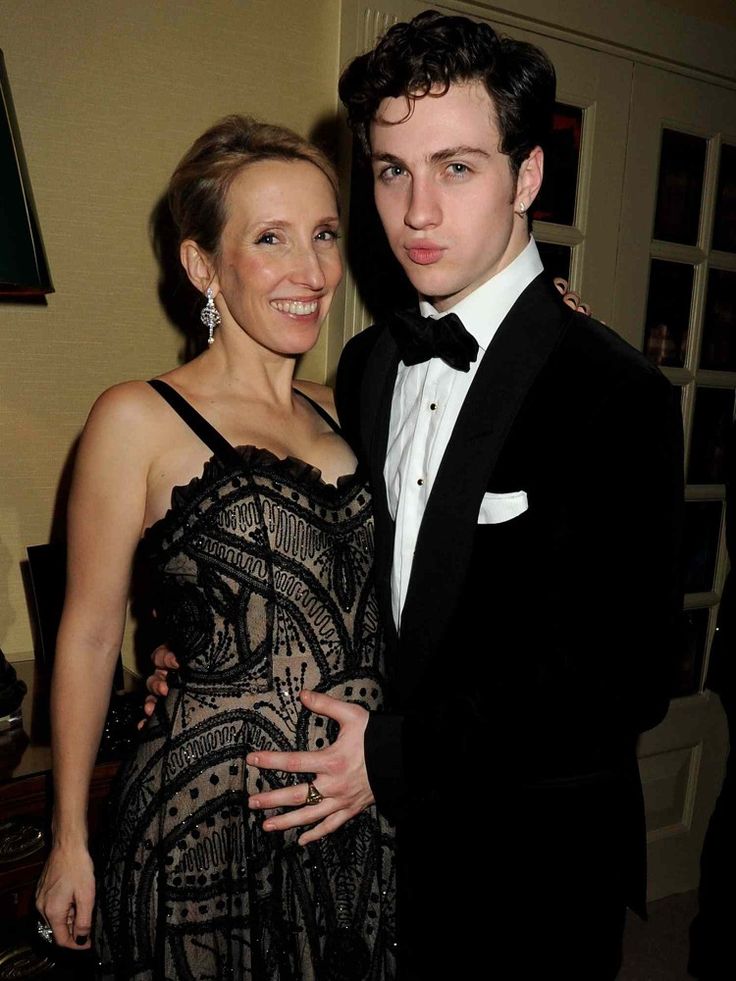 a man in a tuxedo standing next to a woman