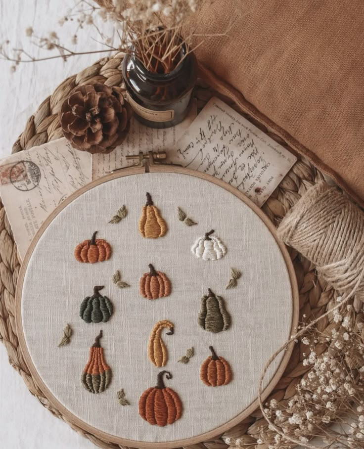 an embroidery kit with pumpkins and leaves on it, next to some twine