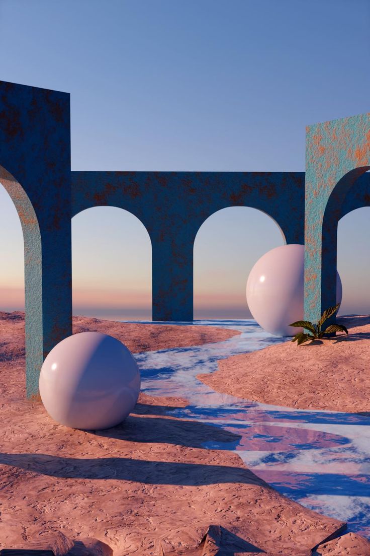 two large white balls sitting next to each other on top of a sandy beach near an arch