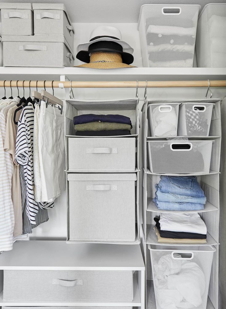 an organized closet with white drawers and plastic bins filled with clothes, hats, and other items