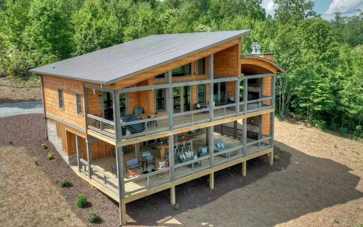 an aerial view of a wooden house in the middle of trees and dirt area with stairs leading up to it