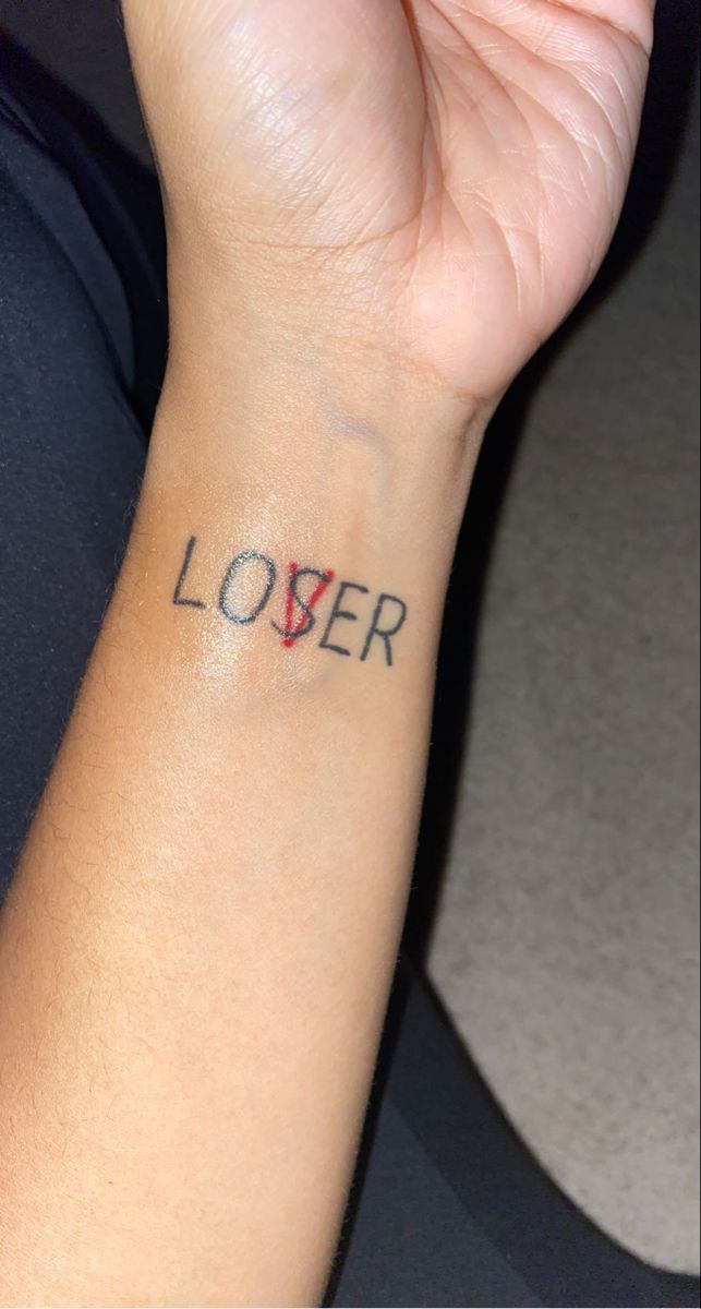 a woman's wrist tattoo with the word lover written on her left arm and an arrow in the middle