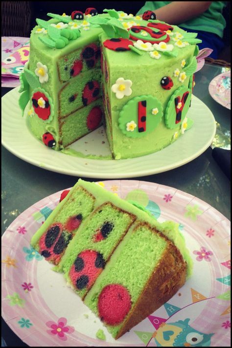 there is a green cake with ladybugs on it and one slice has been cut out