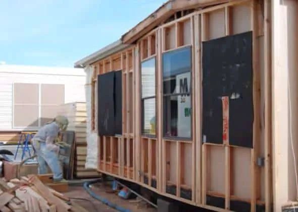 a man is working on the side of a house being built with wood and siding