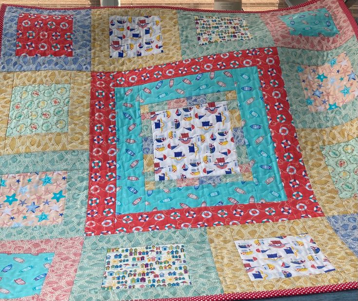 a quilted table topper with many different colors and designs on it, sitting on a wooden bench