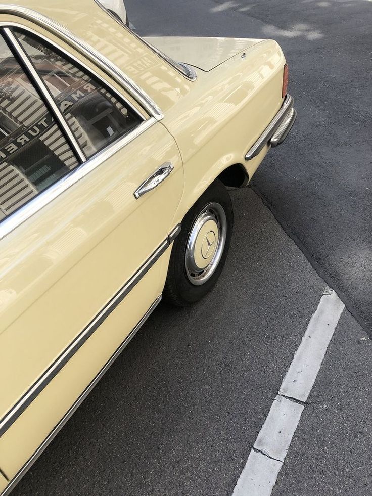 an old yellow car parked on the side of the road next to a parking meter