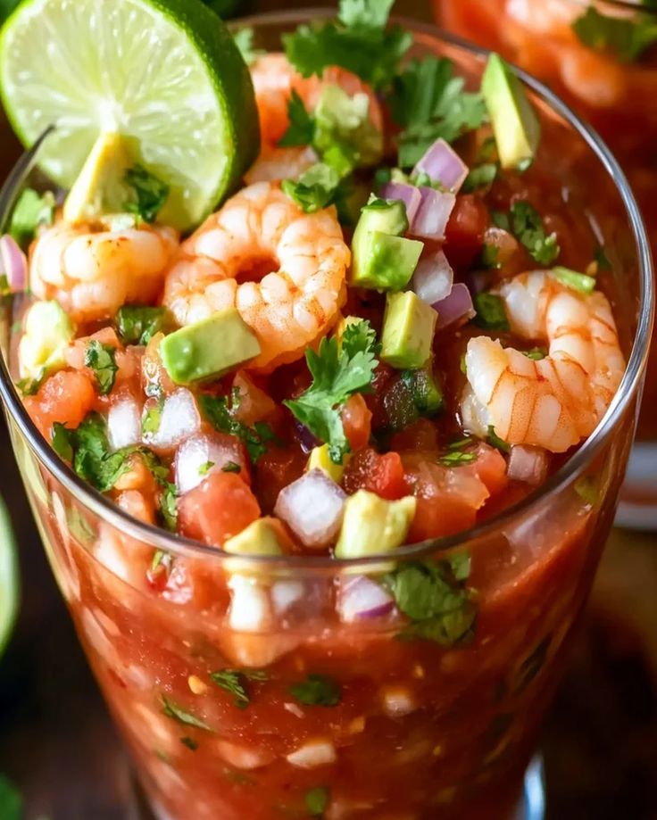 shrimp and avocado salsa in a glass with lime wedges on the side