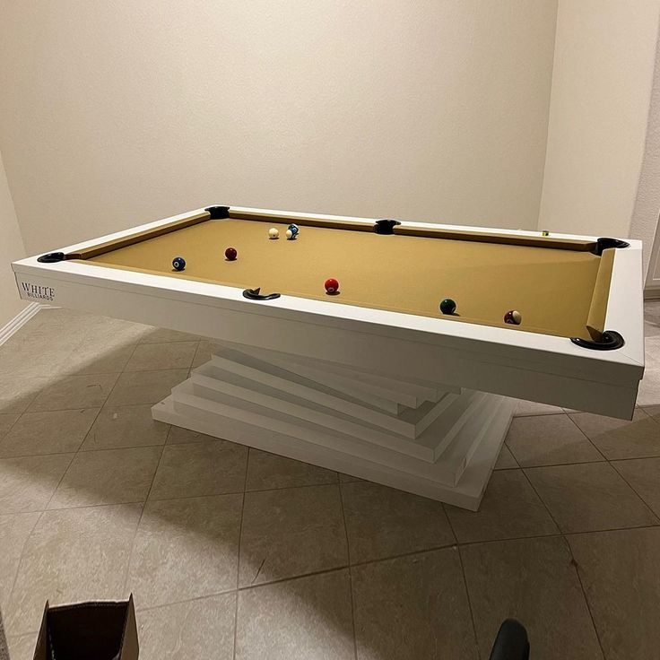 a pool table in the middle of a room with tile flooring and white walls