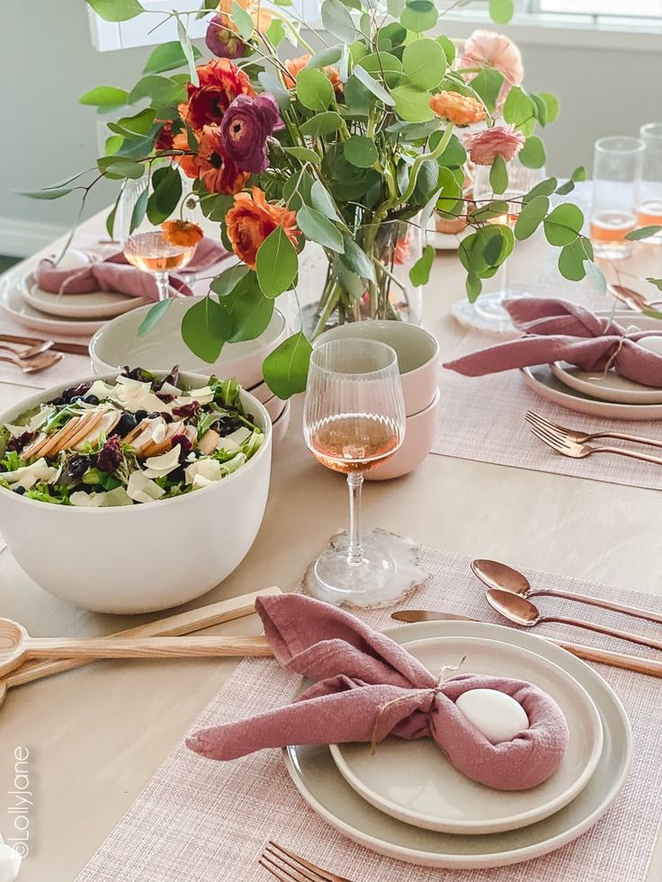 the table is set with plates, silverware and pink napkins for an elegant dinner