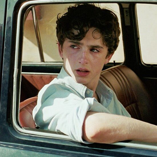 a young man sitting in the driver's seat of a car looking out the window