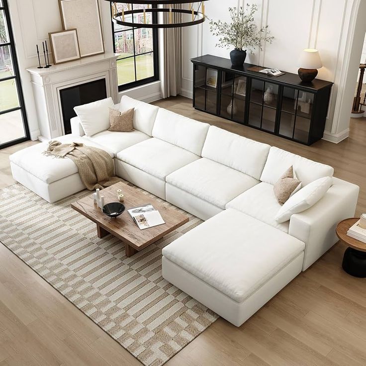 a large white sectional couch sitting in a living room next to a table and fireplace