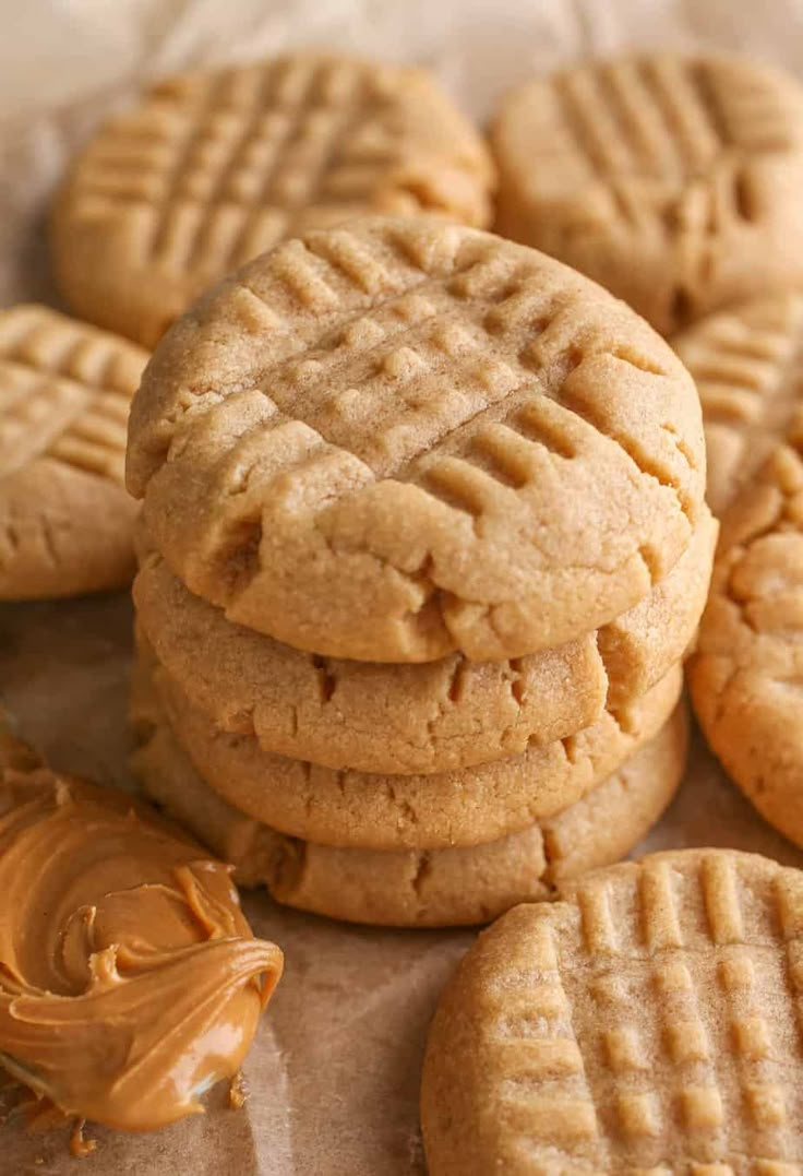 peanut butter cookies stacked on top of each other with the rest of the cookies in front