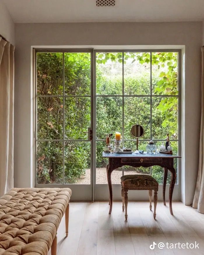 a bedroom with a bed, desk and large glass doors that lead to the outside