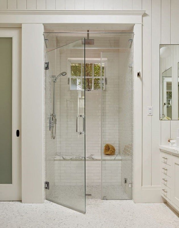 a white bathroom with a walk in shower next to a sink and mirror on the wall