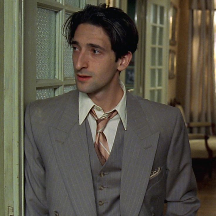 a man wearing a suit and tie standing in front of a door