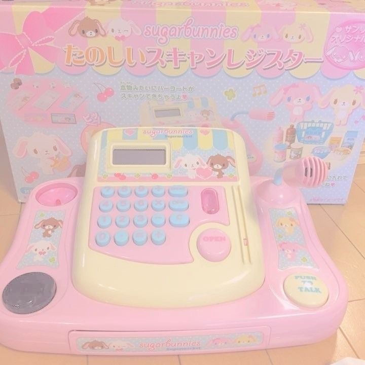 a pink and white toy calculator sitting on top of a wooden floor next to a box