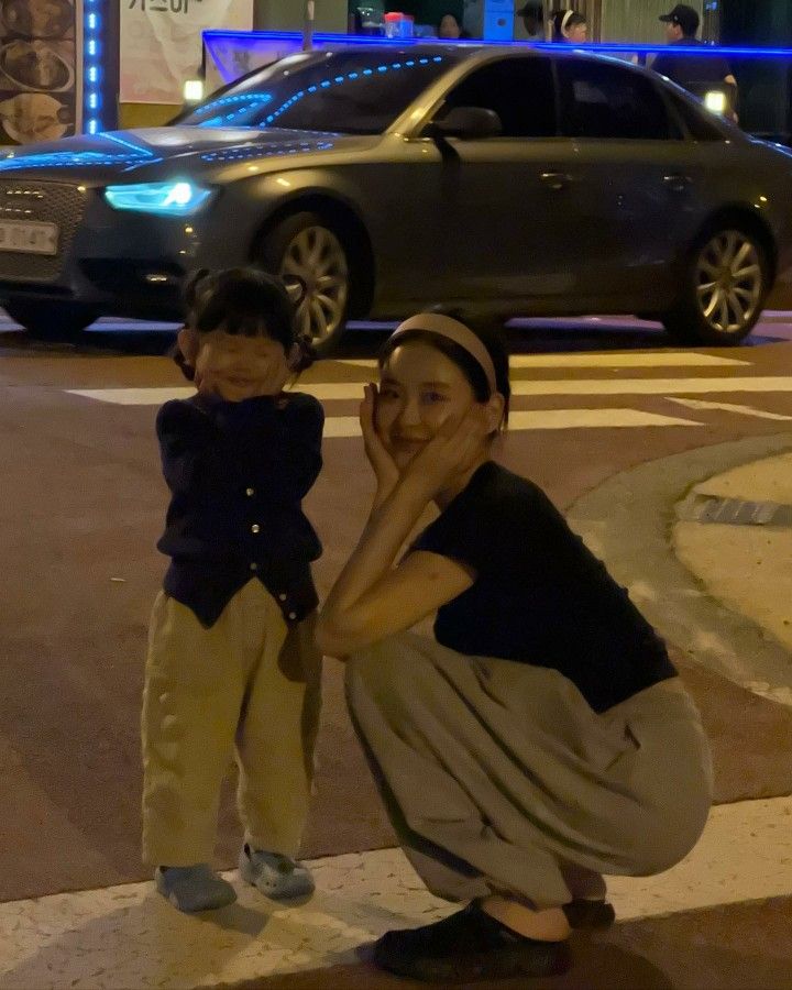 a woman kneeling down next to a little boy on the side of a road at night