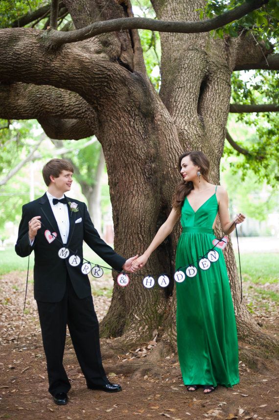 a man and woman holding hands in front of a tree with paper circles on it