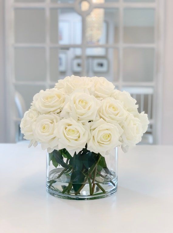 a vase filled with white roses on top of a table