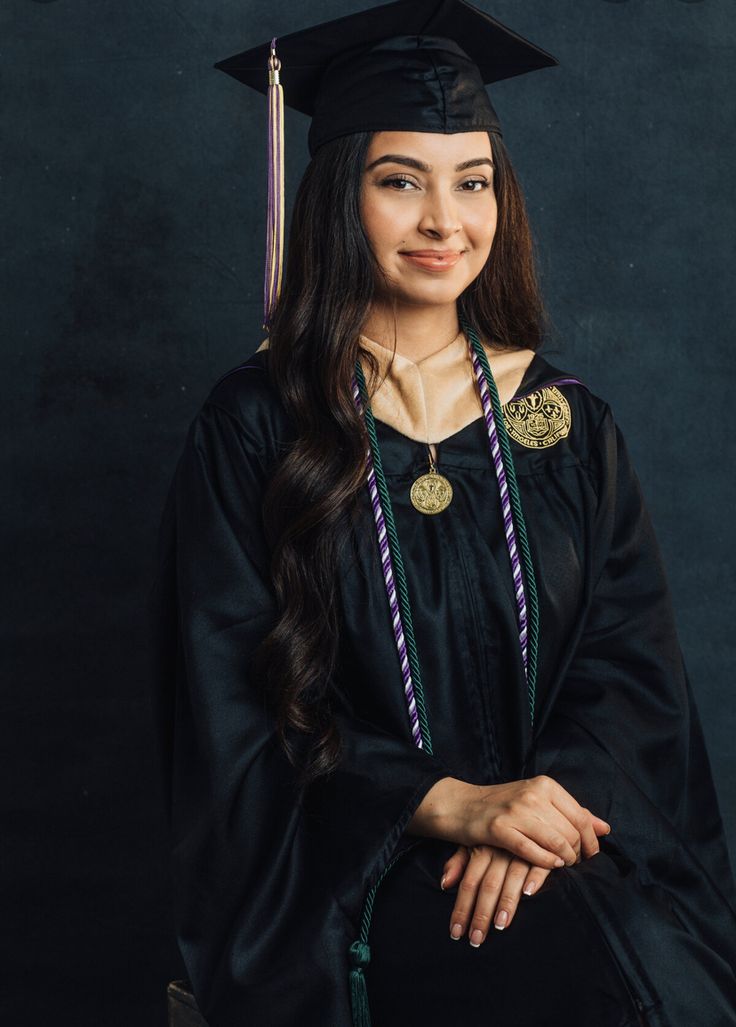 a woman wearing a graduation cap and gown posing for a photo in front of a black background