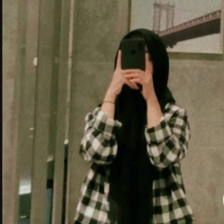 a woman taking a selfie in front of a mirror with her cell phone up to her face